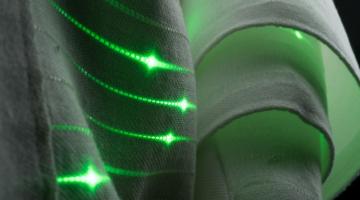In this photograph of fabric, you can see the green light of functional fibers. “No human-made objects are more ubiquitous or exposed to more vital data than the clothes we all wear,” says doctoral student Gabriel Locke. “Wouldn’t it b...